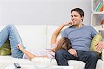 Cute and happy young couple relaxing on sofa at home