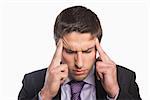 Close-up of a young tensed businessman suffering from headache against white background