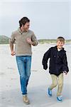 Full length of a young man and son jogging at the beach