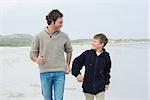 Happy young man and cheerful son jogging at the beach