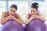 Portrait of two fit women with exercise balls at a bright gym