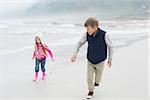 Full length of a happy brother and sister running at the beach