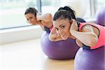 Portrait of two fit young women exercising on fitness balls in the bright gym