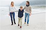 Full length portrait of a happy family of three walking at the beach