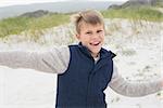 Portrait of a cheerful young boy running at the beach