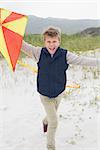 Portrait of a cheerful young boy with kite at the beach