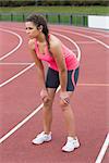 Full length of a young sporty wFull length of a young sporty woman taking a break while jogging on the running trackoman taking a break while jogging on the running track