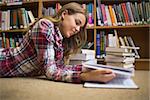 Smiling student lying on library floor reading in college