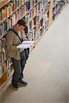 Student reading a book standing in library  at the university