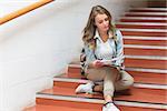 Pretty student sitting on stairs looking at camera in college