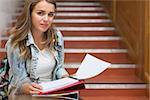 Smiling young student sitting on stairs looking at camera in college