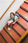 Young student sitting on stairs smiling up at camera in college