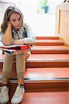 Troubled student sitting on stairs in college
