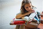 Sad student sitting on stairs in college