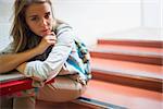 Sad lonely student sitting on stairs looking at camera in college