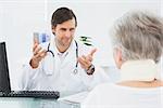 Smiling male doctor listening to senior patient with concentration at the medical office