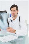 Concentrated male doctor looking at x-ray picture of lungs in the medical office