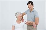 Male physiotherapist massaging a smiling senior woman's arm in the medical office