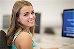 Pretty student smiling at camera in the computer room in college