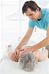 Close-up of a physiotherapist massaging a senior woman's back in the medical office