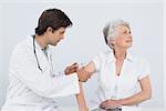 Male doctor injecting a senior female patient's arm over white background