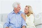 Relaxed cheerful loving senior couple sitting on sofa in a house