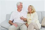 Relaxed cheerful senior couple watching television in a house