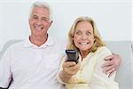 Relaxed shocked senior couple watching television in a house