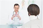 Friendly male doctor listening to patient with concentration at desk in medical office