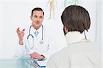 Friendly male doctor in communication with patient at desk in medical office