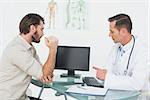 Male doctor in conversation with patient at desk in medical office