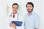 Portrait of a male doctor and patient with reports in the medical office