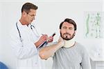 Male doctor examining a patient's sprained neck in the medical office
