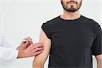 Close-up of hands injecting a young male patient's arm over white background