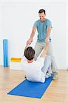 Male therapist assisting young man with stretching exercises in the medical office