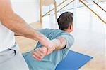 Physical therapist assisting young man with stretching exercises in the gym hospital