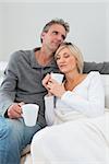 Relaxed man and woman with coffee cups in the living room at home