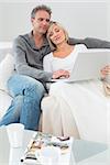 Relaxed man and woman using laptop in the living room at home