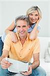 Happy man and woman reading newspaper in the living room at home