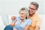 Happy man and woman doing the newspaper crossword puzzle in the living room at home