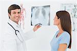 Portrait of a smiling male doctor explaining lungs x-ray to female patient in the medical office