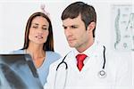 Male doctor explaining lungs x-ray to female patient in the medical office