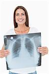 Portrait of a smiling young woman holding lung x-ray over white background