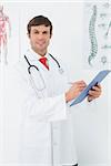 Portrait of a confident male doctor holding clipboard in the medical office