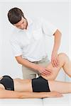 Male physiotherapist examining a young woman's leg in the medical office