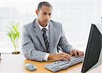 Concentrated young businessman using computer at office desk