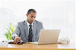 Concentrated young businessman using laptop at the office desk