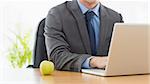 Mid section of a smartly dressed businessman with laptop sitting at office desk