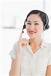 Portrait of a beautiful smiling female executive with headset in a bright office