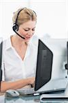 Concentrated female executive with headset using computer at office desk